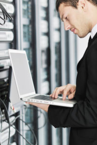 young it engeneer business man with thin modern aluminium laptop in network server room